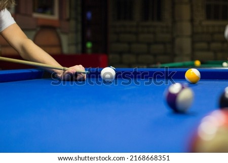 Billiard pool game in progress, player aims to shoot balls with cue Royalty-Free Stock Photo #2168668351
