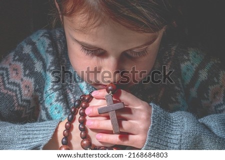 Prayer to God. Young beautiful girl pray with rosary.