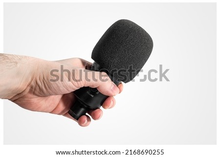 Hand with a microphone on the background. Concept for voice recording, interviewing, music making. Editing and improving music.