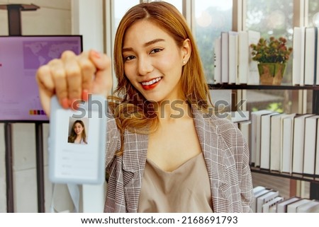 Portrait cute and beautiful asian female employee new member financial company gladly presents lanyard style profile photo ID card on the neck for self identification in the office. Royalty-Free Stock Photo #2168691793