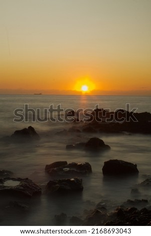 Long exposure picture taken from the beach during sunset with volcanic rocks in the foreground