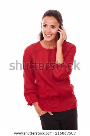 Portrait of alone adult brunette on red shirt speaking on her phone while standing and smiling on isolated white background