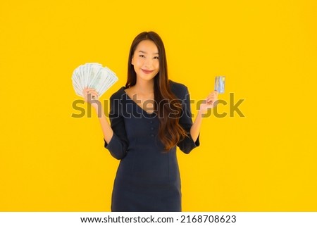Portrait beautiful young asian woman with cash and credit card on yellow isolated background