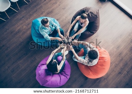 Top angle view photo of cheerful cute groupmates sitting dormitory bean bags showing v-signs indoors workstation workshop Royalty-Free Stock Photo #2168712711