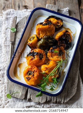 Roasted sweet yellow bell peppers on white enamel tray with coriander leaves. Top View