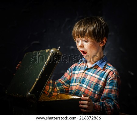 Little boy finding treasure inside a suitcase Royalty-Free Stock Photo #216872866
