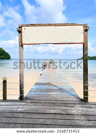Wooden sign arch and wooden bridge in the blue sea, sea view.