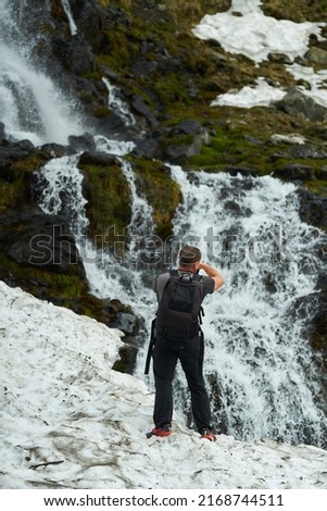 Nature photographer shooting a waterfall through the snow