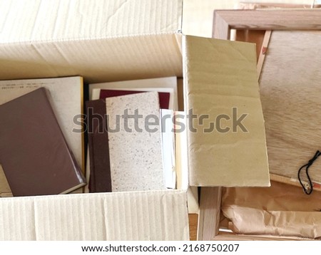 Books and frames in a cardboard box in bird's-eye view Royalty-Free Stock Photo #2168750207