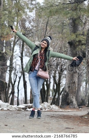 A portrait of a young Indian woman posing and enjoying in Gulmarg, Jammu and Kashmir, India. The woman is wearing winter jacket.