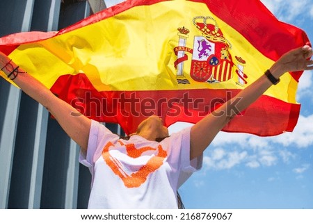 Young woman smiling with the Spanish flag. Happy young adult waving a flag. She looks up