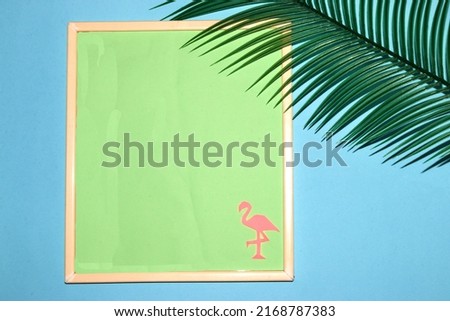  frame with pastel green background as copy space, on the background and pink flamingos, next to the frame flame leaf, creative summer design