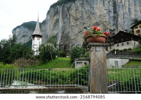 Selective focus picture of rose in vase with from Staubbach Falls and buildings insight. A must place to visit in Switzerland.