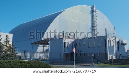 Sarcophagus over the destroyed reactor of the Chernobyl nuclear power plant. Giant metal hangar, radiation protection. No people, windy weather. Royalty-Free Stock Photo #2168797719