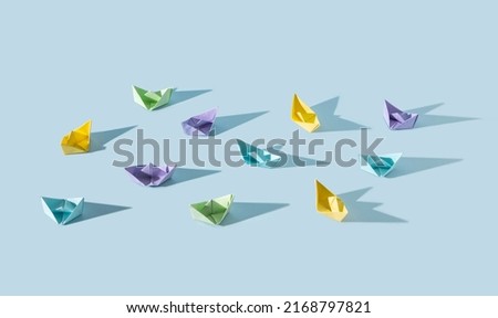Pastel colour small paper boats with long shadow on blue background. Vacation and travel together concept.