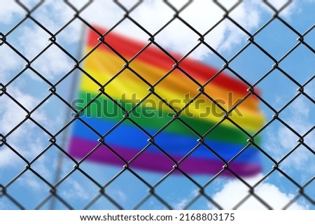 A steel mesh against the background of a blue sky and a flagpole with flag of lgbt pride Royalty-Free Stock Photo #2168803175
