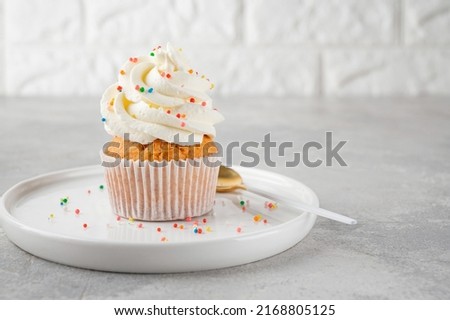 Delicious vanilla cupcakes with cream cheese and sugar candy on a gray background. Dessert for birthday. selective focus, copy space