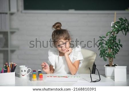 Little girls drawing a colorful pictures with pencil crayons in school classroom. Painting kids. Funny kids face.