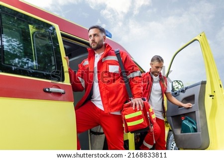 Paramedic nurse and emergency doctor at ambulance with kit. a paramedic, standing at the rear of an ambulance, by the open doors. Royalty-Free Stock Photo #2168833811