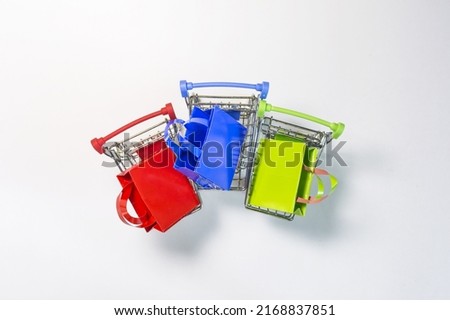 Business concept metal baskets with colored bags of green, red and blue colors on a light background of the copy space.