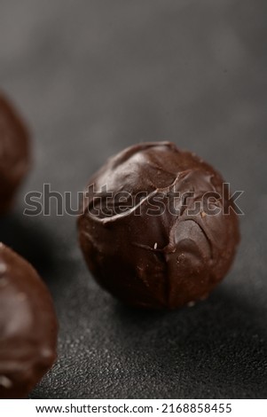 Dark brown chocolate balls on the black background. Delicious chocolates. Close-up picture of chocolate balls.  