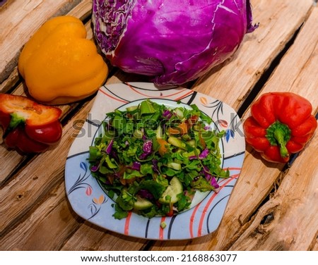 Picture of a plate of salad with fresh vegetables on a wooden floor