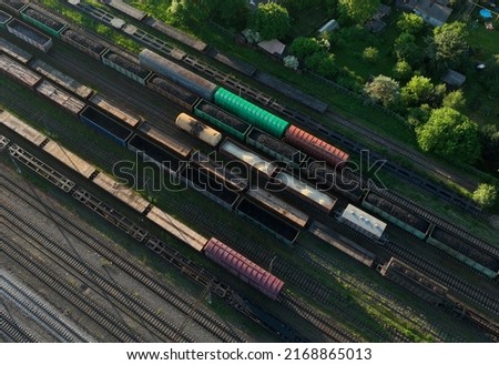 Railway yard with freight rail wagons. Cargo trains with goods on railroad. Freight train with petroleum tank cars and shipping containers. Train yard, aerial view. Rail Freight Shipping Logistics.  Royalty-Free Stock Photo #2168865013