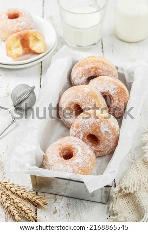 Donuts on a tray with fine granulated sugar topping on light wooden background with copy space, blurry background, selective focus 