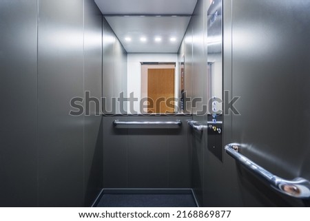 Stainless steel elevator cabin interior with mirror. Modern passenger lift with convenient control panel in building. Transportation concept. Accessible environment for disabled people Royalty-Free Stock Photo #2168869877