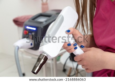 Women's hands hold a device working with carbon peeling.