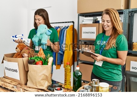 Mother and daughter wearing volunteer uniform writing on checklist working at charity center