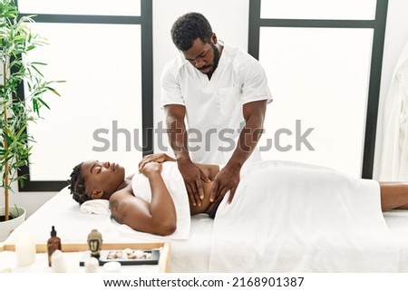 Young physiotherapist man giving abdominal massage to african american woman at the clinic Royalty-Free Stock Photo #2168901387