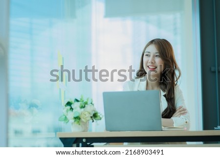 Young Asian businesswoman working with laptop computer on office desk and freely typing notebook. Lifestyle of women studying online business and education ideas