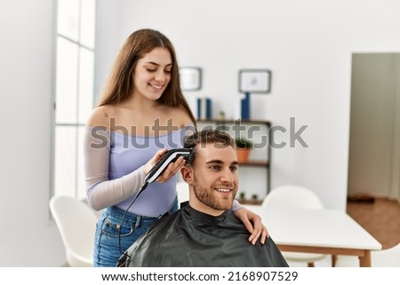 Young woman cutting hair her boyfriend at home. Royalty-Free Stock Photo #2168907529