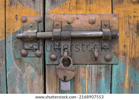 old iron lock on the gate, old wooden planks with shabby paint, close-up detail of a hanging padlock