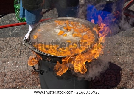 a cauldron on fire in which fish soup is cooked