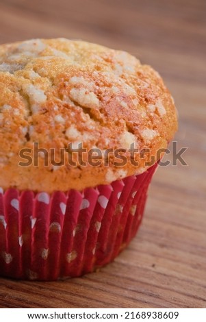 vertical photo of a freshly baked muffin, on a rustic wooden bac