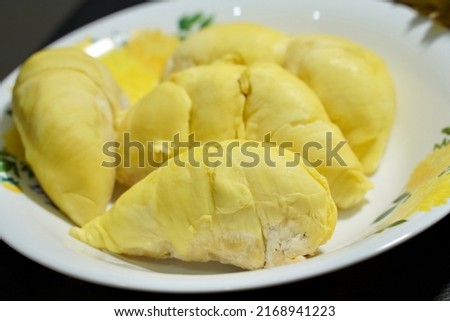 Fresh durian in packaging on white dish with durian peel on banner black  background. Durian king of fruit. Tropical fruit. Topview of ripe durian, wood cutting and rind on table