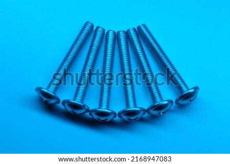 Set of six screws on a light blue background. Macro photo.
Background picture.
