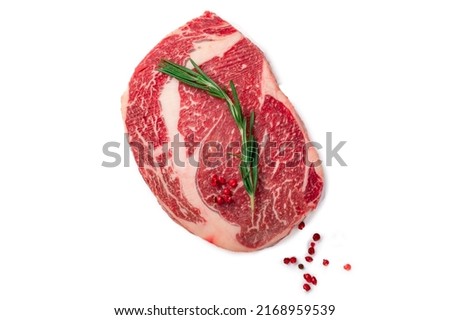 Raw rib eye steak of marbled beef with rosemary and red pepper isolated on a white background