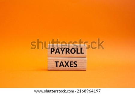 Payroll taxes symbol. Concept word Payroll taxes on wooden blocks. Beautiful orange background. Business and Payroll taxes concept. Copy space