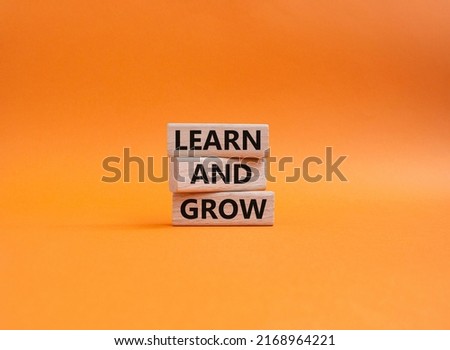 Learn and grow symbol. Concept words 'Learn and grow' on wooden blocks. Beautiful orange background. Business and Learn and grow concept. Copy space. Royalty-Free Stock Photo #2168964221
