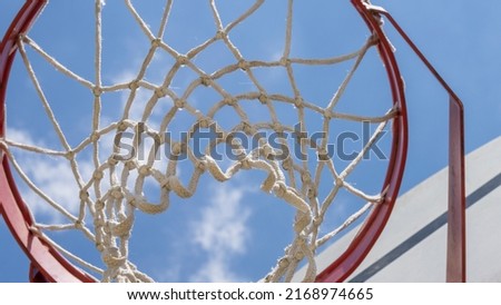 Close-up of a basketball hoop seen from below, blue sky in the background