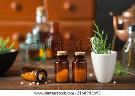 Bottles of homeopathic granules, cabinet with homeopathic remedies and tincture bottles on background. Homeopathy medicine concept.  Royalty-Free Stock Photo #2168983695
