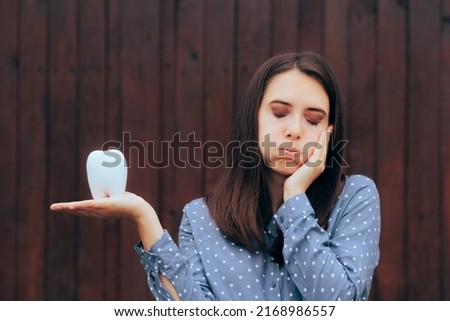 
Unhappy Woman Suffering a Toothache Holding a Molar. Patient feeling pain after wisdom tooth infection 

 Royalty-Free Stock Photo #2168986557