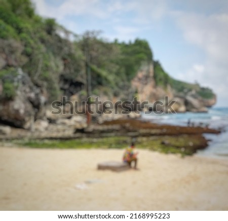 defocused abstract background sitting man on rock enjoying the beach in Yogyakarta with white sand and coral reef beside.
