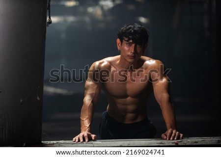 Portrait of Strong Asian sportsman athlete in sportswear do sport training workout bodybuilding exercise in abandoned building. Shirtless man bodybuilder practicing muscular build in dark place gym Royalty-Free Stock Photo #2169024741