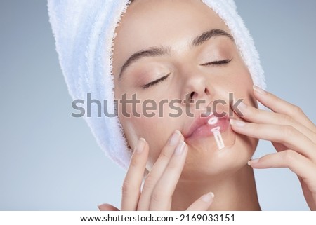 Plumping up those lips. Studio shot of an attractive young woman using a limp plumper against a grey background. Royalty-Free Stock Photo #2169033151