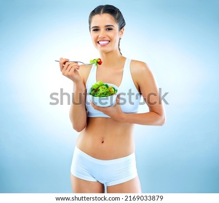 Dont eat less, eat right. Studio portrait of an attractive young woman eating a salad against a blue background. Royalty-Free Stock Photo #2169033879
