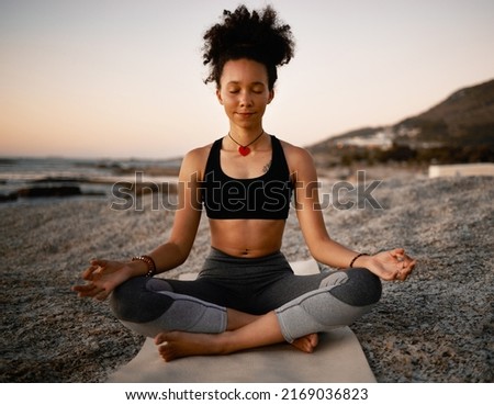Ultimate zen. Full length shot of an attractive young woman practicing yoga on the beach at sunset.